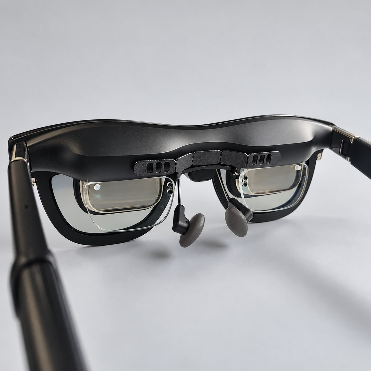 SGG BREEZE six-slot bracket installed inside XREAL One Pro glasses: three rectangular openings per end, six total. Glasses and insert frame shown for installation context.