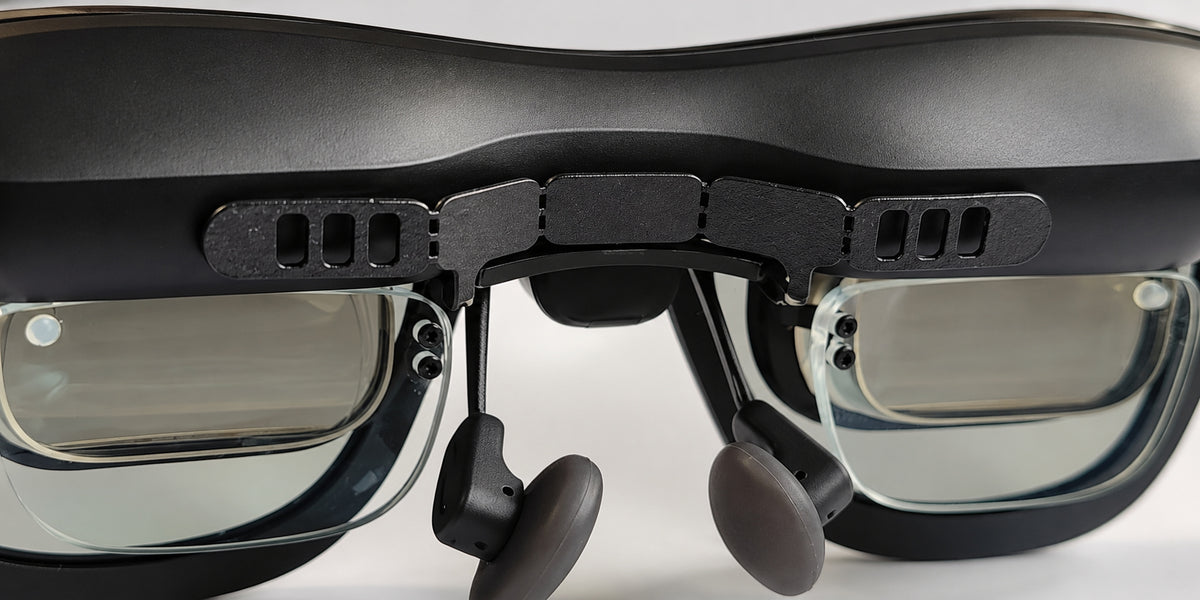 SGG BREEZE six-slot bracket installed inside XREAL One Pro glasses: three rectangular openings per end, six total. Glasses and insert frame shown for installation context.